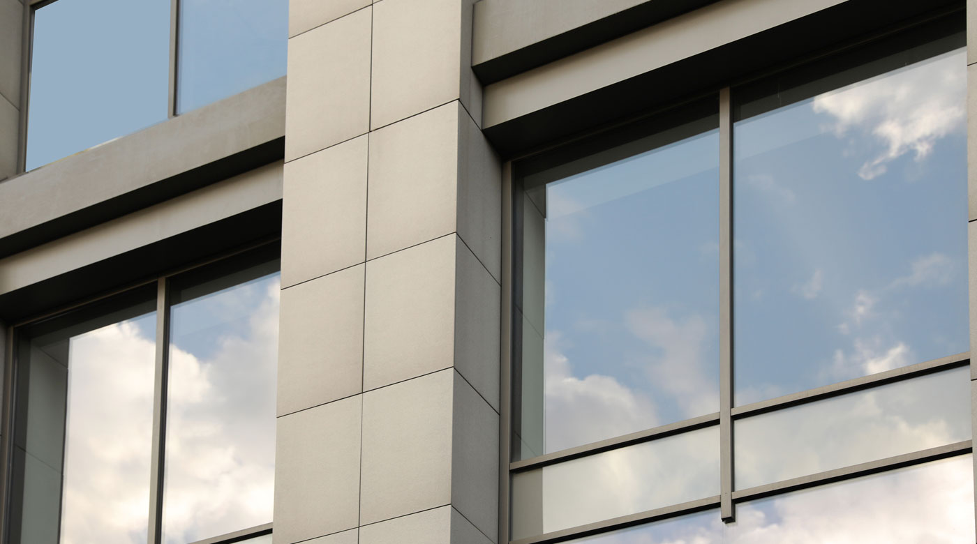 The clouds reflect in the tinted glass windows of a building