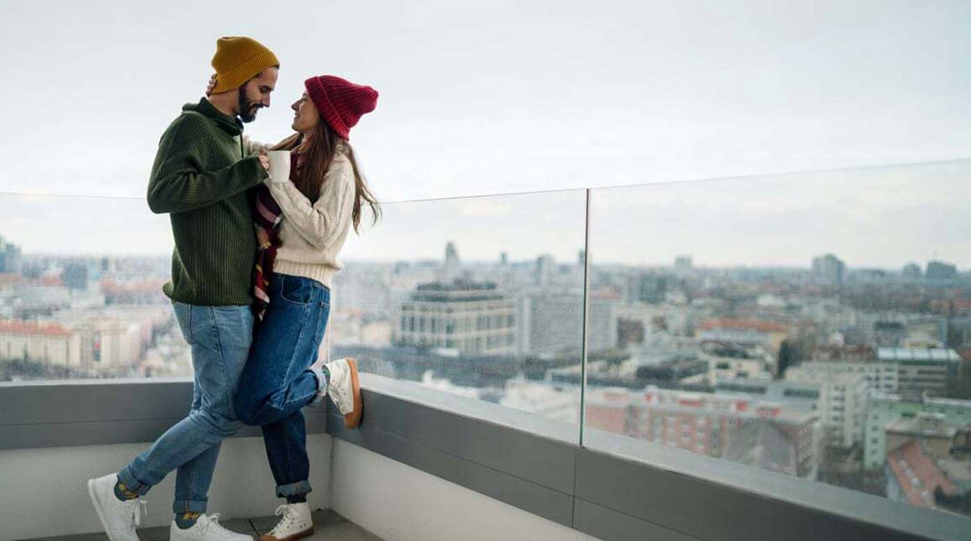 A couple enjoys a beautiful day on the deck with glass railings.