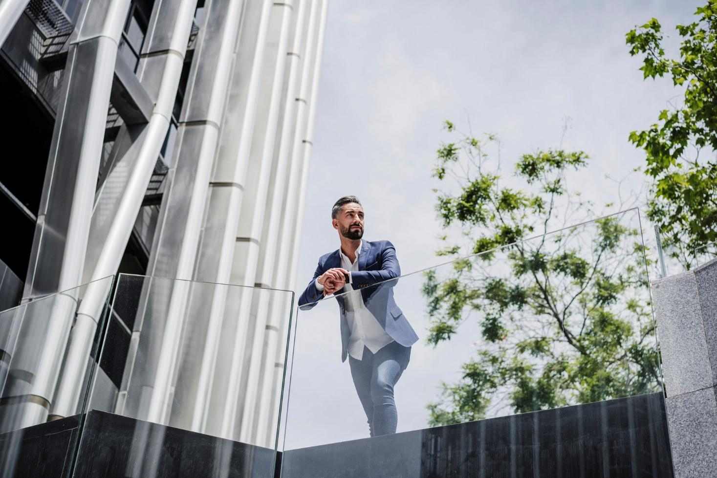 A young man is leaning on glass railing.
