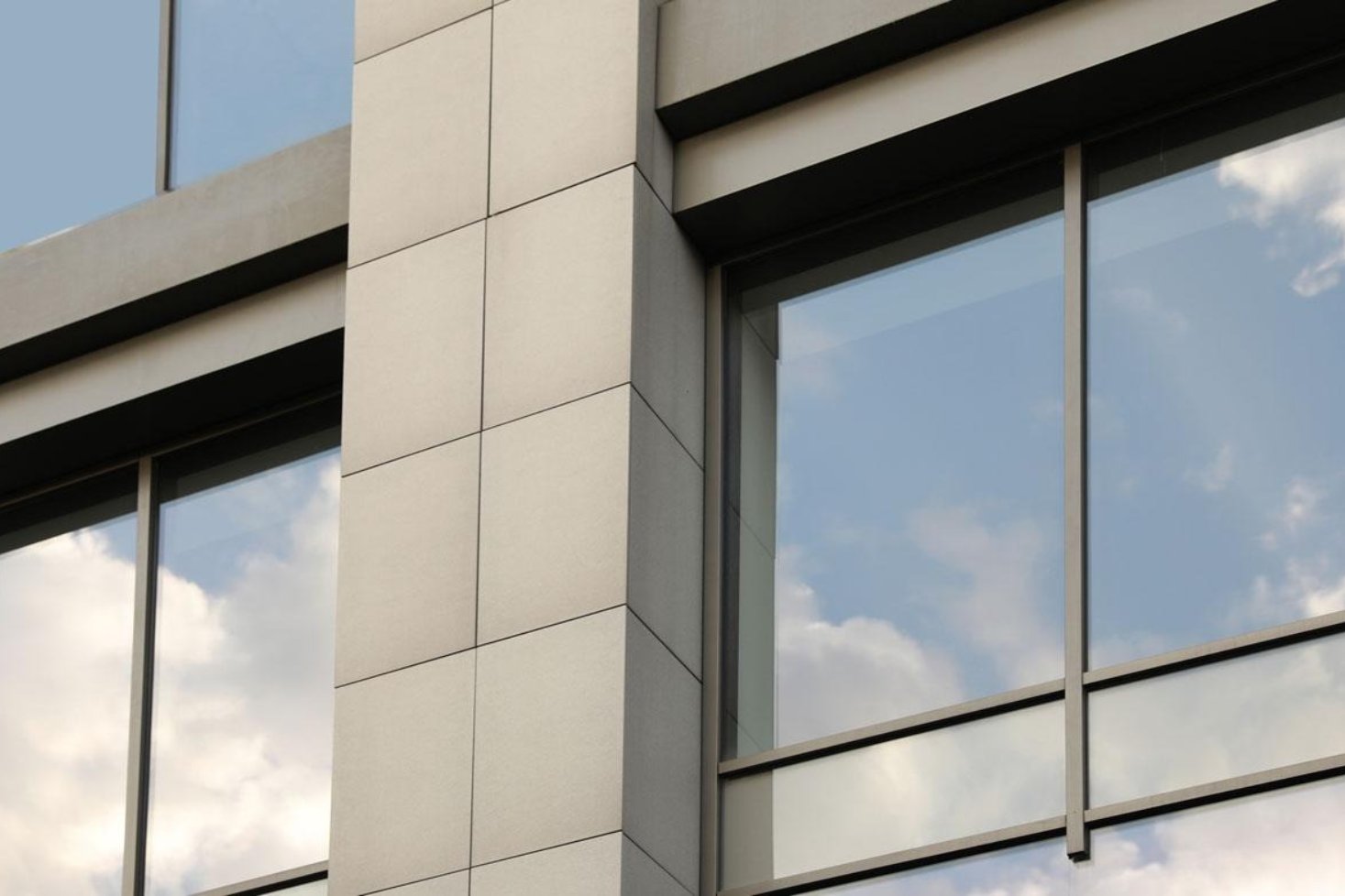 The clouds reflect in the tinted glass windows of a building.
