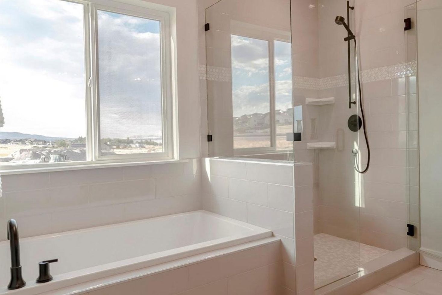 Frameless glass shower enclosure with bathtub and modern bathroom interior.