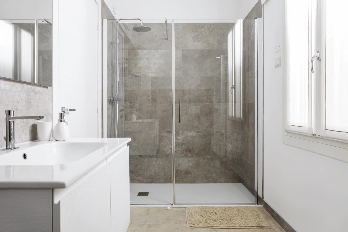 Modern bathroom with frameless glass shower and neutral tile walls.