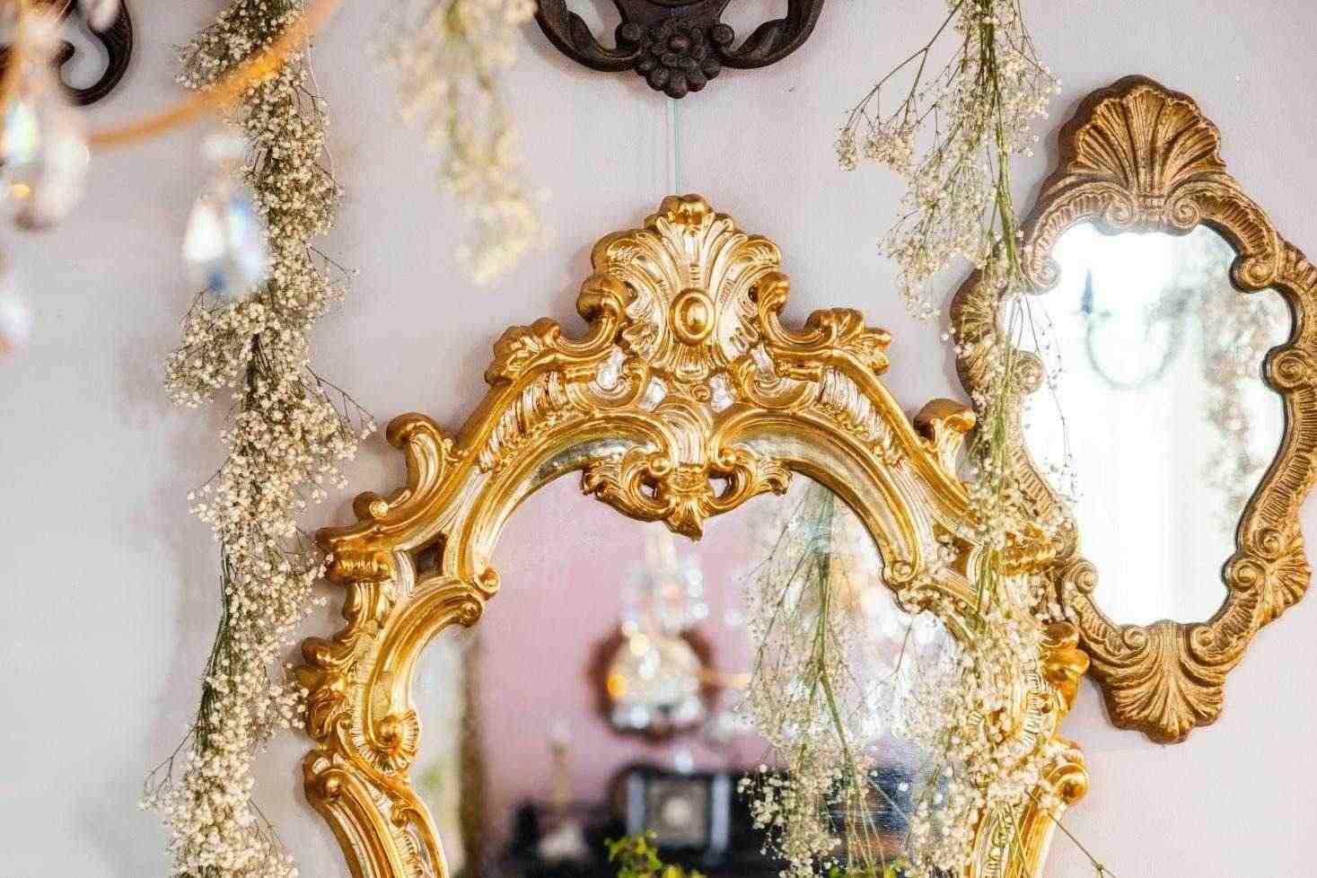 Ornate gold antique mirror with carved frame and floral accents in a vintage-inspired interior